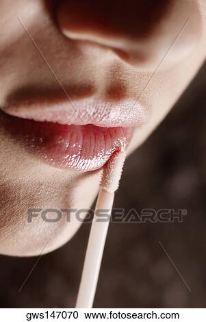 Close-up of a young woman applying lipstick View Large Photo Image Stock Image - Close-up of a young woman applying lipstick. Fotosearch