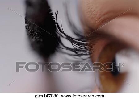 Stock Image - Close-up of a young woman applying mascara. Fotosearch