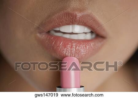 Close-up of a young woman applying lipstick View Large Photo Image Stock Photo - Close-up of a young woman applying lipstick. Fotosearch