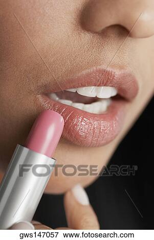 Stock Photo - Close-up of a young woman applying lipstick. Fotosearch
