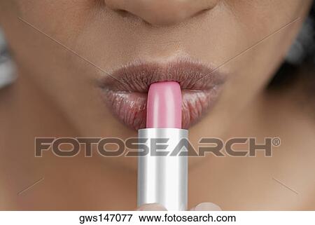 Close-up of a young woman applying lipstick View Large Photo Image Stock Photo - Close-up of a young woman applying lipstick. Fotosearch