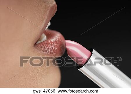 Close-up of a young woman applying lipstick View Large Photo Image Stock Photograph - Close-up of a young woman applying lipstick. Fotosearch