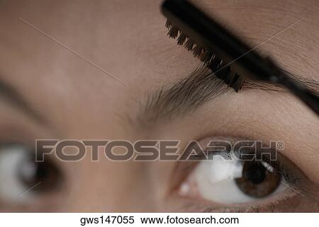 Close-up of a young woman applying make-up on her eyebrow View Large Photo Image Stock Photography - Close-up of a young woman applying make-up on her eyebrow. Fotosearch