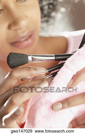 Stock Photo - Close-up of a young woman taking make-up brushes from her purse. Fotosearch
