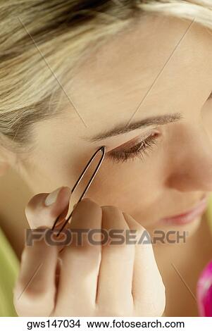 Close-up of a young woman tweezing her eyebrows View Large Photo Image Picture - Close-up of a young woman tweezing her eyebrows. Fotosearch