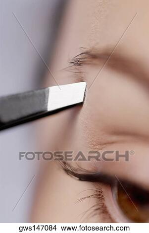 Close-up of a young woman tweezing her eyebrow View Large Photo Image Picture - Close-up of a young woman tweezing her eyebrow. Fotosearch