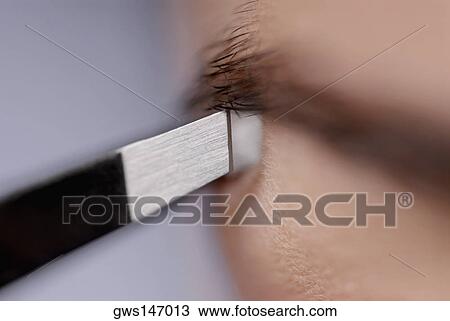 Close-up of a young woman tweezing her eyebrow View Large Photo Image Stock Image - Close-up of a young woman tweezing her eyebrow. Fotosearch