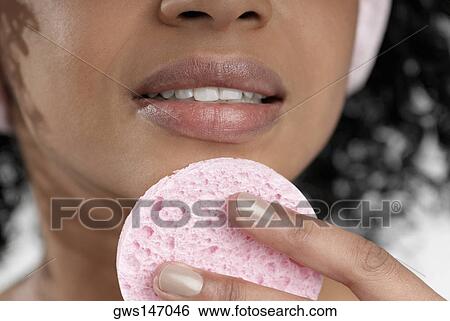 Stock Photograph - Close-up of a young woman using a powder puff. Fotosearch