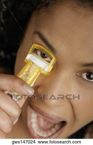 Close-up of a young woman using an eyelash curler View Large Photo Image Picture - Close-up of a young woman using an eyelash curler. Fotosearch