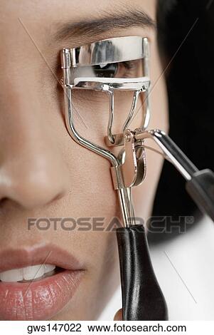 Close-up of a young woman using an eyelash curler View Large Photo Image Stock Image - Close-up of a young woman using an eyelash curler. Fotosearch