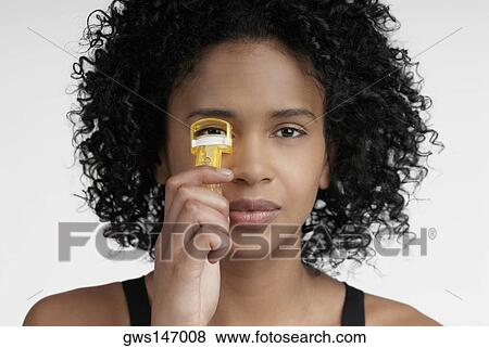 Close-up of a young woman using an eyelash curler View Large Photo Image Stock Photo - Close-up of a young woman using an eyelash curler. Fotosearch