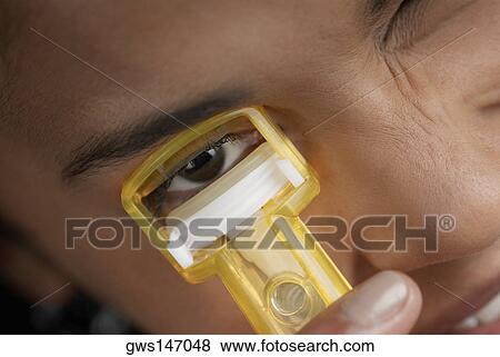 Close-up of a young woman using an eyelash curler View Large Photo Image Stock Photo - Close-up of a young woman using an eyelash curler. Fotosearch
