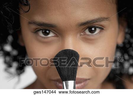 Portrait of a young woman applying blush with a brush View Large Photo Image Picture - Portrait of a young woman applying blush with a brush. Fotosearch