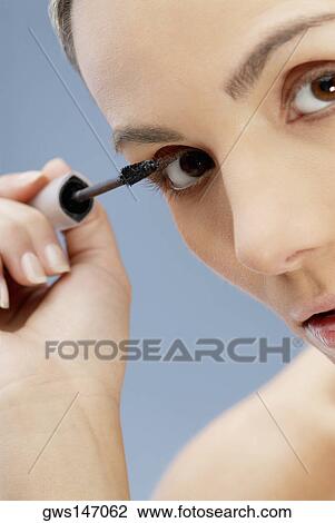 Portrait of a young woman applying mascara View Large Photo Image Stock Image - Portrait of a young woman applying mascara. Fotosearch