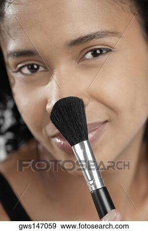 Portrait of a young woman applying blush with a brush View Large Photo Image Stock Photo - Portrait of a young woman applying blush with a brush. Fotosearch