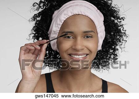 Portrait of a young woman applying mascara View Large Photo Image Stock Photography - Portrait of a young woman applying mascara. Fotosearch
