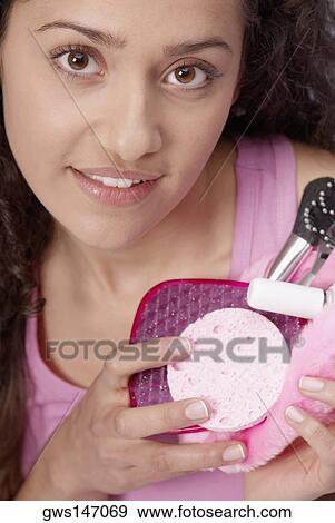 Portrait of a young woman holding a makeup bag View Large Photo Image Stock Photo - Portrait of a young woman holding a makeup bag. Fotosearch