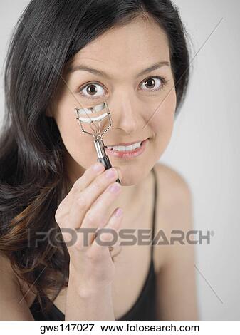 Portrait of a young woman holding an eyelash curler View Large Photo Image Stock Photo - Portrait of a young woman holding an eyelash curler. Fotosearch
