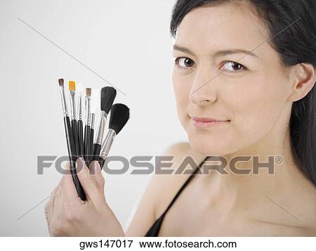 Portrait of a young woman holding make-up brushes View Large Photo Image Stock Photo - Portrait of a young woman holding make-up brushes. Fotosearch