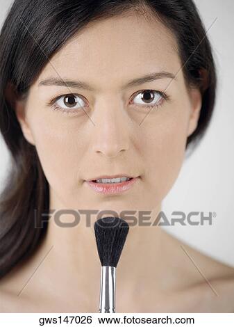 Portrait of a young woman touching a make-up brush to her chin View Large Photo Image Stock Photograph - Portrait of a young woman touching a make-up brush to her chin. Fotosearch