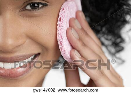 Stock Image - Portrait of a young woman using a powder puff. Fotosearch