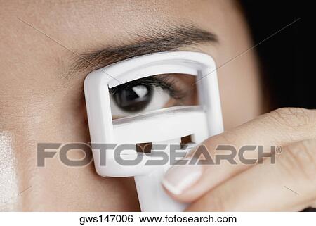 Portrait of a young woman using an eyelash curler View Large Photo Image Stock Photograph - Portrait of a young woman using an eyelash curler. Fotosearch
