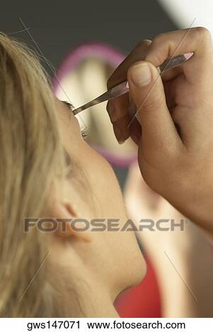 Rear view of a young woman tweezing her eyebrows View Large Photo Image Stock Image - Rear view of a young woman tweezing her eyebrows. Fotosearch