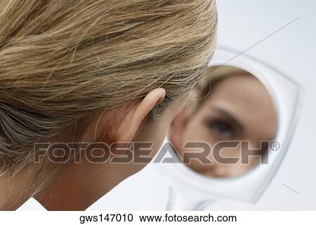 Stock Image - Reflection of a young woman's face in a vanity mirror. Fotosearch