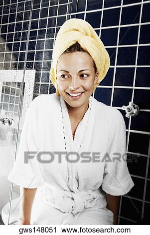 Stock Image - Close-up of a young woman sitting in the bathroom and smiling. Fotosearch