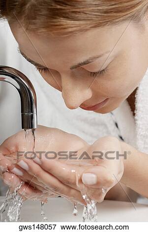 Close-up of a young woman washing her face in the bathroom sink View Large Photo Image Stock Photo - Close-up of a young woman washing her face in the bathroom sink. Fotosearch