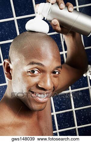 Stock Photo - Portrait of a young man spraying shaving cream on his head. Fotosearch