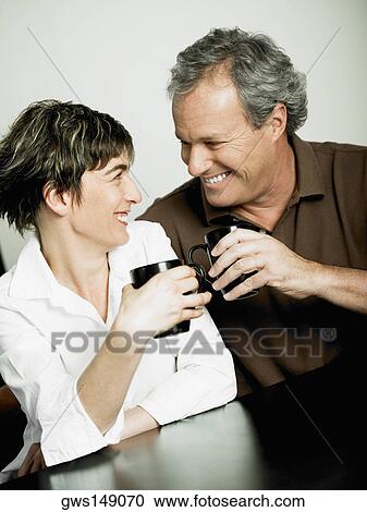 Close-up of a mature couple holding cups of coffee and looking at each other View Large Photo Image Stock Image - Close-up of a mature couple holding cups of coffee and looking at each other. Fotosearch