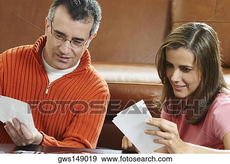 Stock Photo - Close-up of a mature man and a mid adult woman looking at photographs. Fotosearch