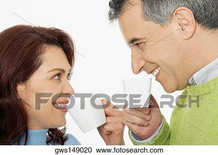 Close-up of a mid adult couple holding tea cups and smiling View Large Photo Image Stock Image - Close-up of a mid adult couple holding tea cups and smiling. Fotosearch