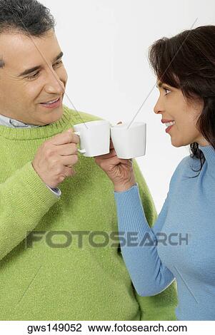 Close-up of a mid adult couple holding tea cups and smiling View Large Photo Image Stock Image - Close-up of a mid adult couple holding tea cups and smiling. Fotosearch