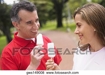 Stock Photo - Close-up of a mid adult couple holding two ice creams. Fotosearch