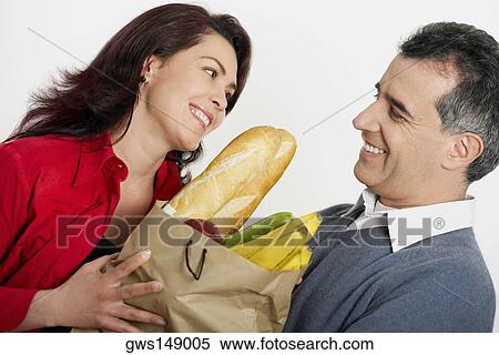 Stock Photography - Close-up of a mid adult couple holding a shopping bag and smiling. Fotosearch