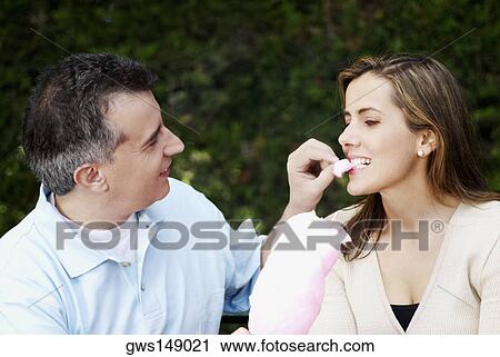Close-up of a mid adult man feeding cotton candy to a mid adult woman View Large Photo Image Stock Image - Close-up of a mid adult man feeding cotton candy to a mid adult woman. Fotosearch
