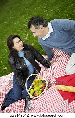 High angle view of a mid adult couple sitting on a picnic blanket and smiling View Large Photo Image Stock Image - High angle view of a mid adult couple sitting on a picnic blanket and smiling. Fotosearch
