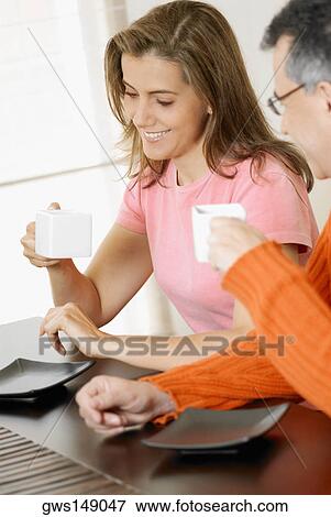 Mid adult couple holding two cups of coffee View Large Photo Image Stock Photo - Mid adult couple holding two cups of coffee. Fotosearch
