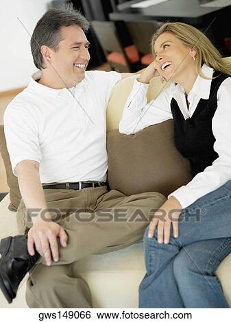 Mid adult woman and a mature man sitting on a couch and looking at each other View Large Photo Image Stock Photograph - Mid adult woman and a mature man sitting on a couch and looking at each other. Fotosearch