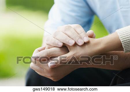 Mid section view of a couple holding hands View Large Photo Image Stock Photo - Mid section view of a couple holding hands. Fotosearch
