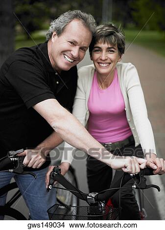 Portrait of a mature couple standing with bicycles and smiling View Large Photo Image Picture - Portrait of a mature couple standing with bicycles and smiling. Fotosearch