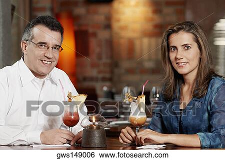 Portrait of a mid adult couple sitting in a restaurant with two glasses of pina colada View Large Photo Image Stock Photograph - Portrait of a mid adult couple sitting in a restaurant with two glasses of pina colada. Fotosearch