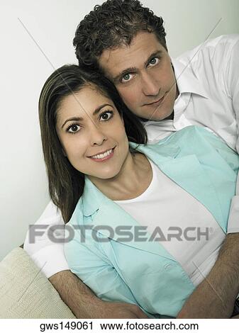 Stock Image - Portrait of a mid adult man embracing a mid adult woman form behind. Fotosearch