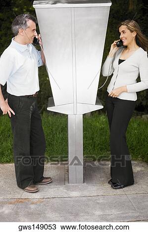 Side profile of a mid adult couple talking on pay phones View Large Photo Image Stock Image - Side profile of a mid adult couple talking on pay phones. Fotosearch