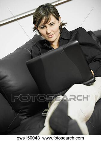 Close-up of a businesswoman reclining on a couch and using a laptop View Large Photo Image Stock Image - Close-up of a businesswoman reclining on a couch and using a laptop. Fotosearch