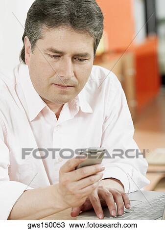 Stock Image - Close-up of a mature man looking at a mobile phone. Fotosearch