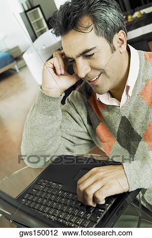 Close-up of a mature man talking on a mobile phone and using a laptop View Large Photo Image Stock Image - Close-up of a mature man talking on a mobile phone and using a laptop. Fotosearch