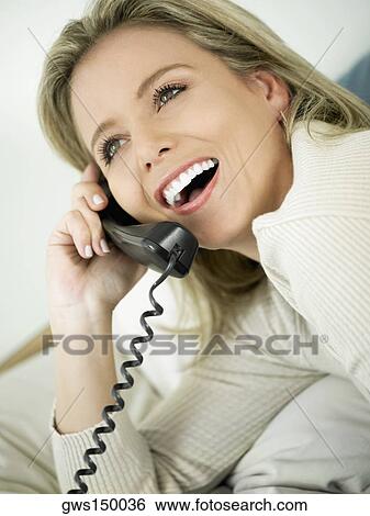 Stock Photograph - Close-up of a mid adult woman talking on the telephone. Fotosearch